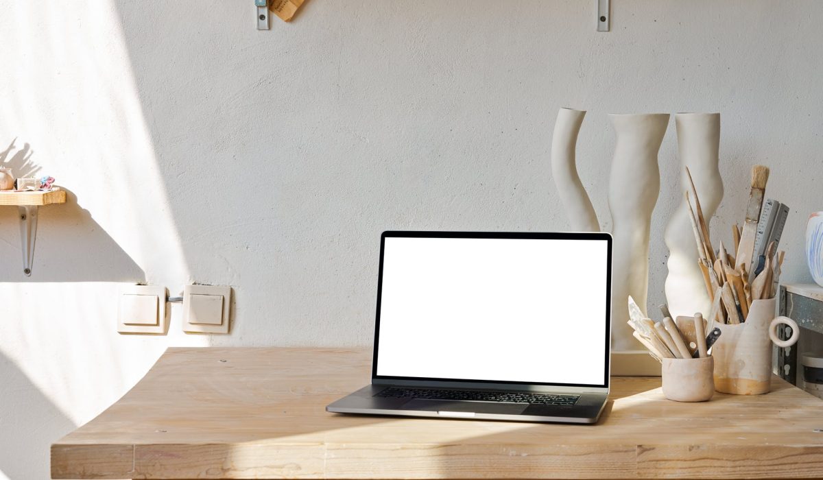 laptop on table near decorative ceramic objects near brushes